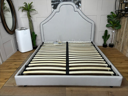 Handmade Joules Thornton super king bed frame in blue, featuring a towering oversized headboard, classic turned dark-wood feet, and all-over heritage upholstery