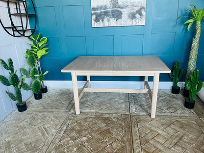 West Elm Hargrove extendable wood dining table shown fully extended, showcasing the smooth, continuous light oak veneer grain patterns and structural support underframe.