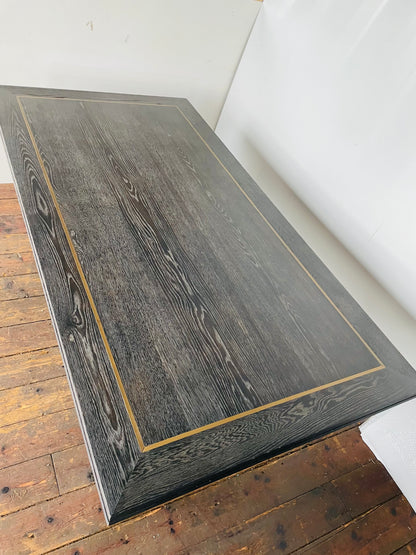 A small rectangular Richmond Interiors Hunter dining table featuring a black oak veneer tabletop with matte brushed gold metal legs and geometric corner inlay details. 