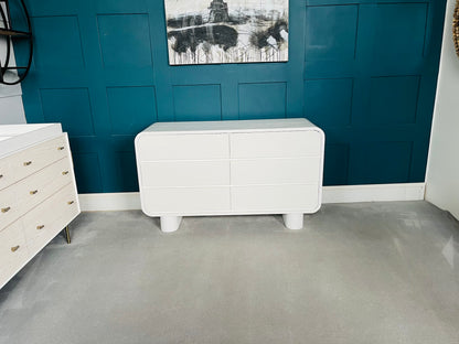Urban Outfitters Huron white mango wood 6-drawer dresser with curved corners and cylindrical feet.