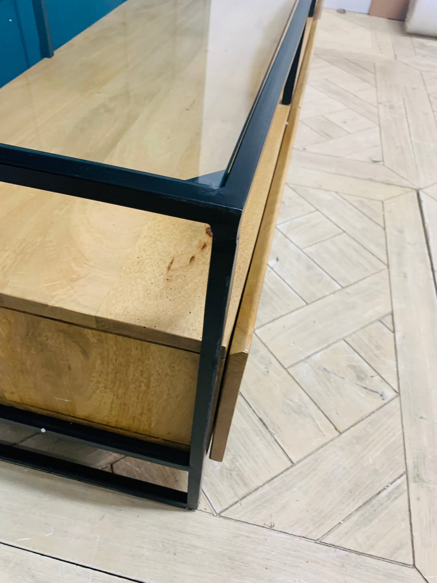 Industrial-style wide TV stand by Made.com, constructed from solid light mango wood with clean black metal lines. The top features a sleek smoked glass surface, and the base includes two roomy drawers for media storage