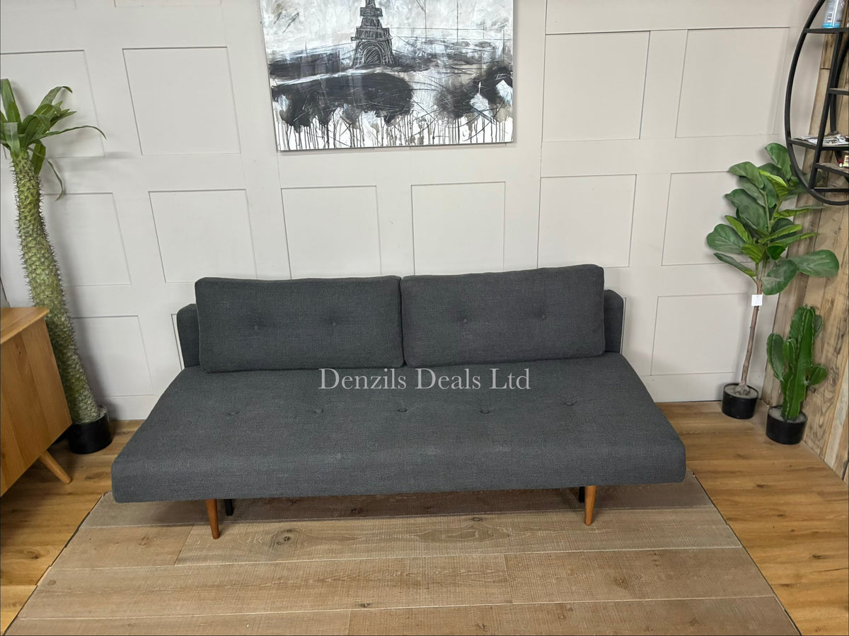 A contemporary mid-century modern style sofa bed by Innovation Living. It features a tailored fabric upholstered seat and backrest with classic button-tufted detailing, two matching rectangular back cushions, and a matte black steel frame supported by tapered, dark stained wood legs."