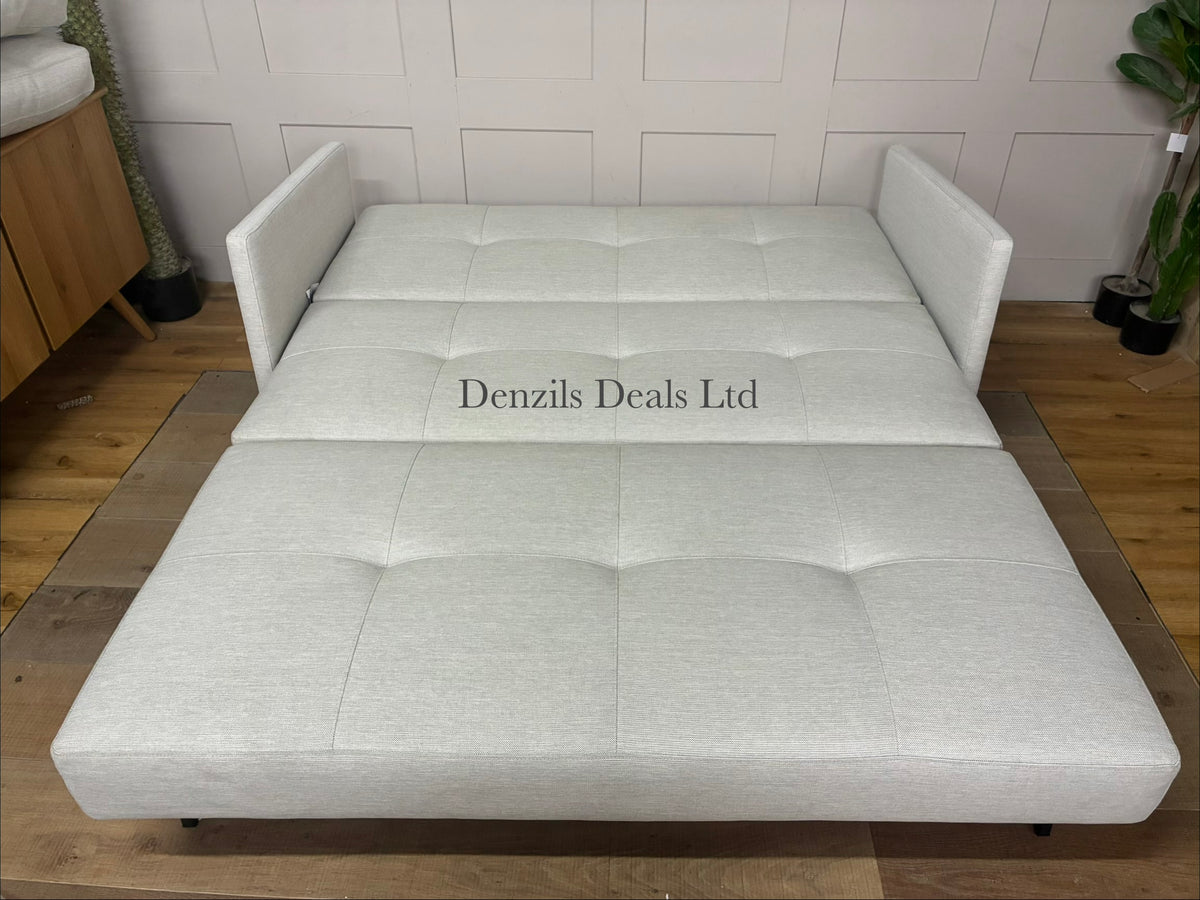 Scandinavian-style sofa bed in textured beige fabric with oak legs, shown as a cozy, compact living room seat.