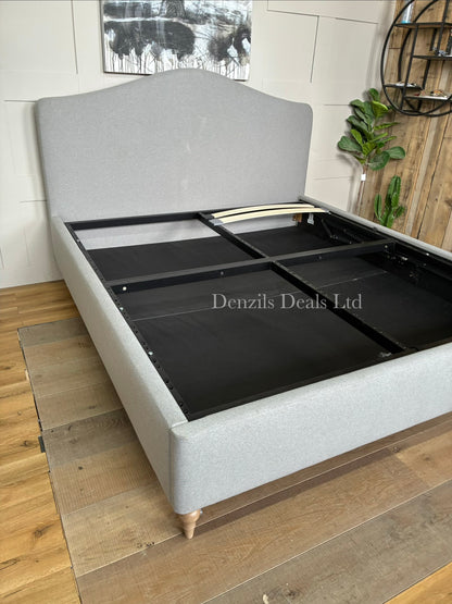 John Lewis Alice Super King ottoman bed frame in Cotton Effect Grey. The bed features a foam-filled, curved headboard with fine-textured grey upholstery and an integrated lifting base for under-bed storage.