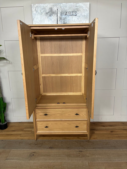 Freestanding John Lewis Bevel Double Wardrobe in a natural light oak finish, featuring two hinged doors with minimalist metal handles, two spacious storage drawers at the base, and distinctive beveled detailing along the edges and plinth.