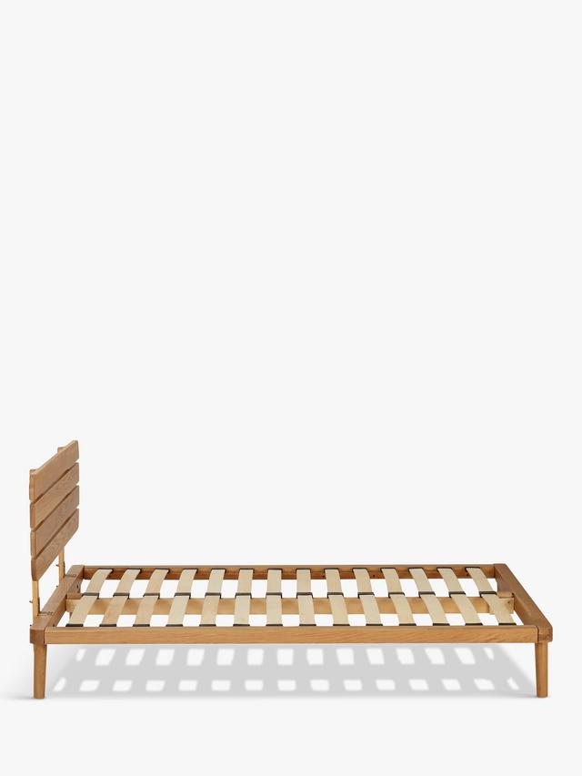 A modern bedroom setup featuring the John Lewis Bow king-size oak bed frame with an upholstered headboard, styled with neutral bedding