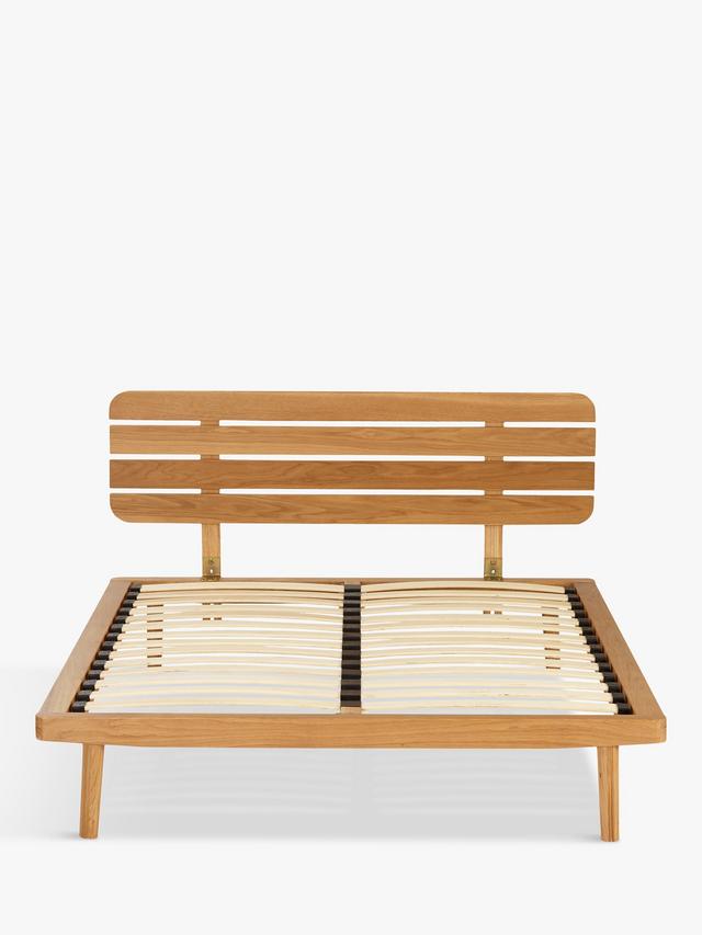 The John Lewis Bow king-size bed frame, crafted from natural grained solid oak and oak veneers, showcasing a soft slatted headboard and a low-profile, minimalist design