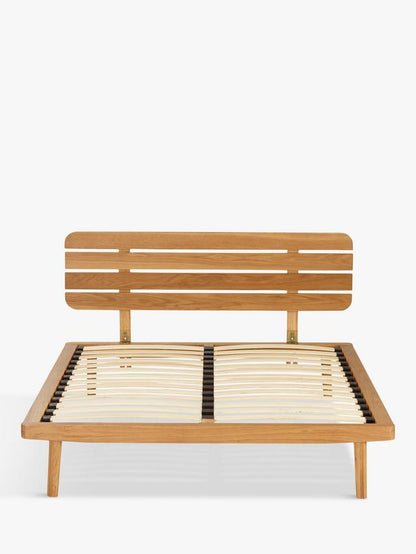 The John Lewis Bow king-size bed frame, crafted from natural grained solid oak and oak veneers, showcasing a soft slatted headboard and a low-profile, minimalist design