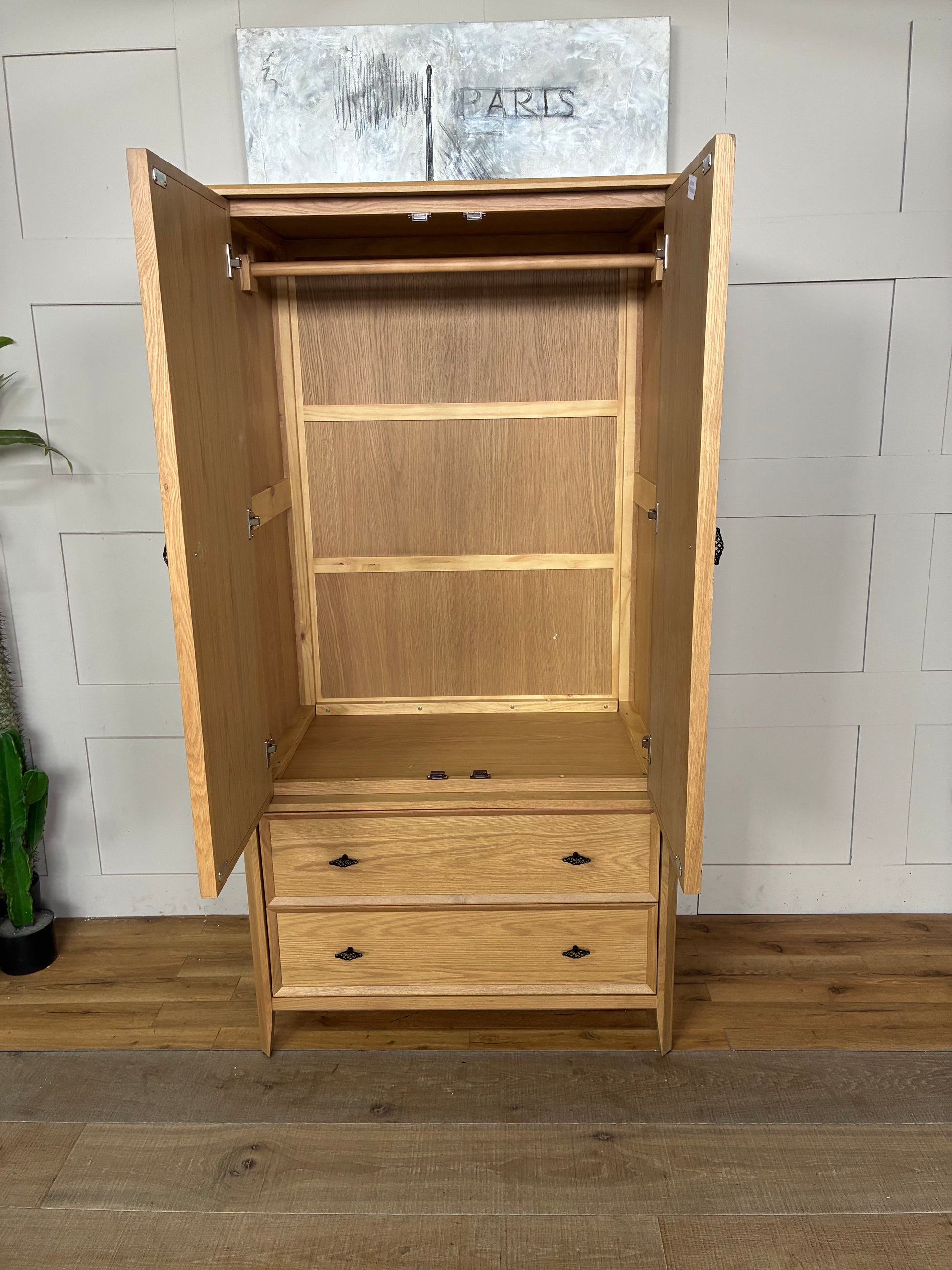 Freestanding John Lewis Bevel Double Wardrobe in a natural light oak finish, featuring two hinged doors with minimalist metal handles, two spacious storage drawers at the base, and distinctive beveled detailing along the edges and plinth.