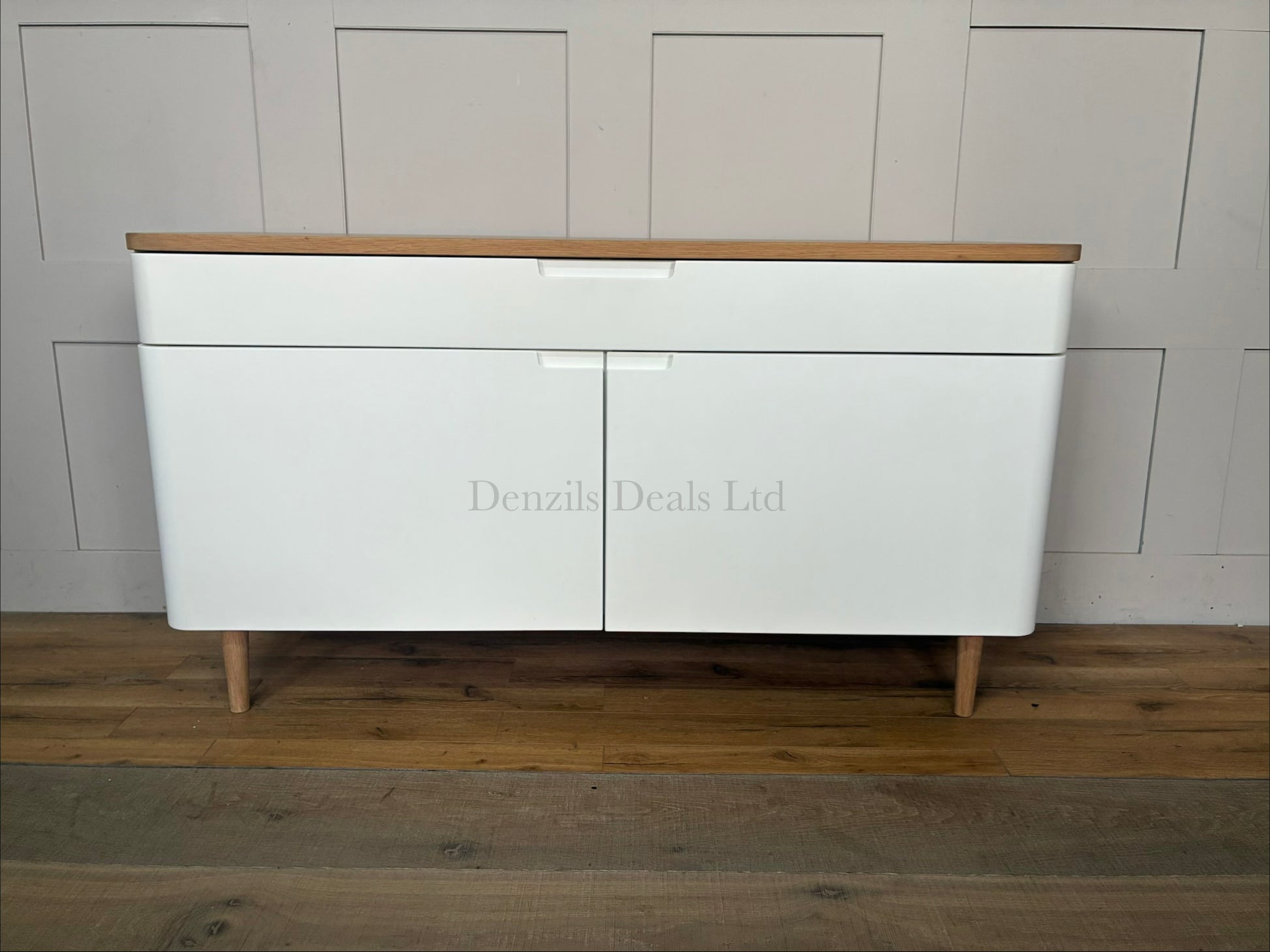 A styled living room featuring the white and oak Ebbe Gehl for John Lewis Mira sideboard positioned against a neutral wall, decorated with home accessories on its wooden top.