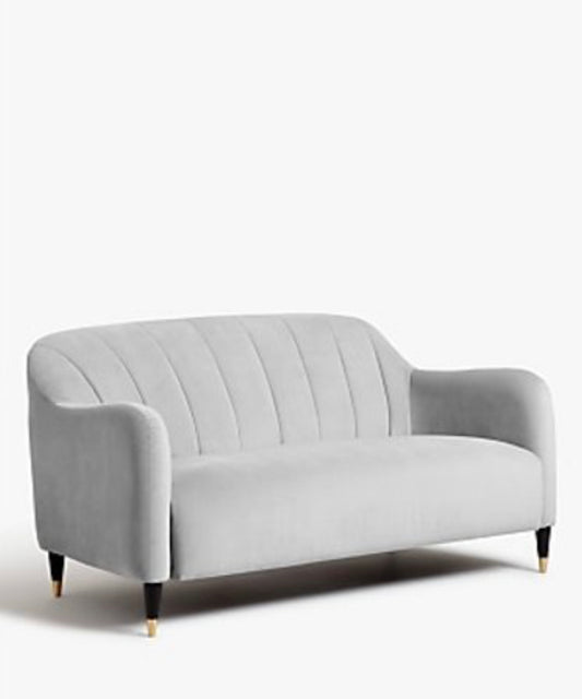 A grey velvet petite sofa with a fluted back and dark brass capped legs.