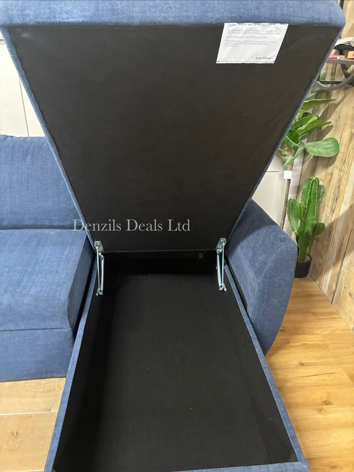 A John Lewis Sansa modular sofa bed with the hinged cushion of the chaise section lifted open, revealing a spacious, hidden built-in storage compartment underneath the seat.