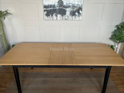 Modern John Lewis Stanton extending dining table featuring a natural light oak rectangular tabletop supported by angular, black metal or painted wooden legs.