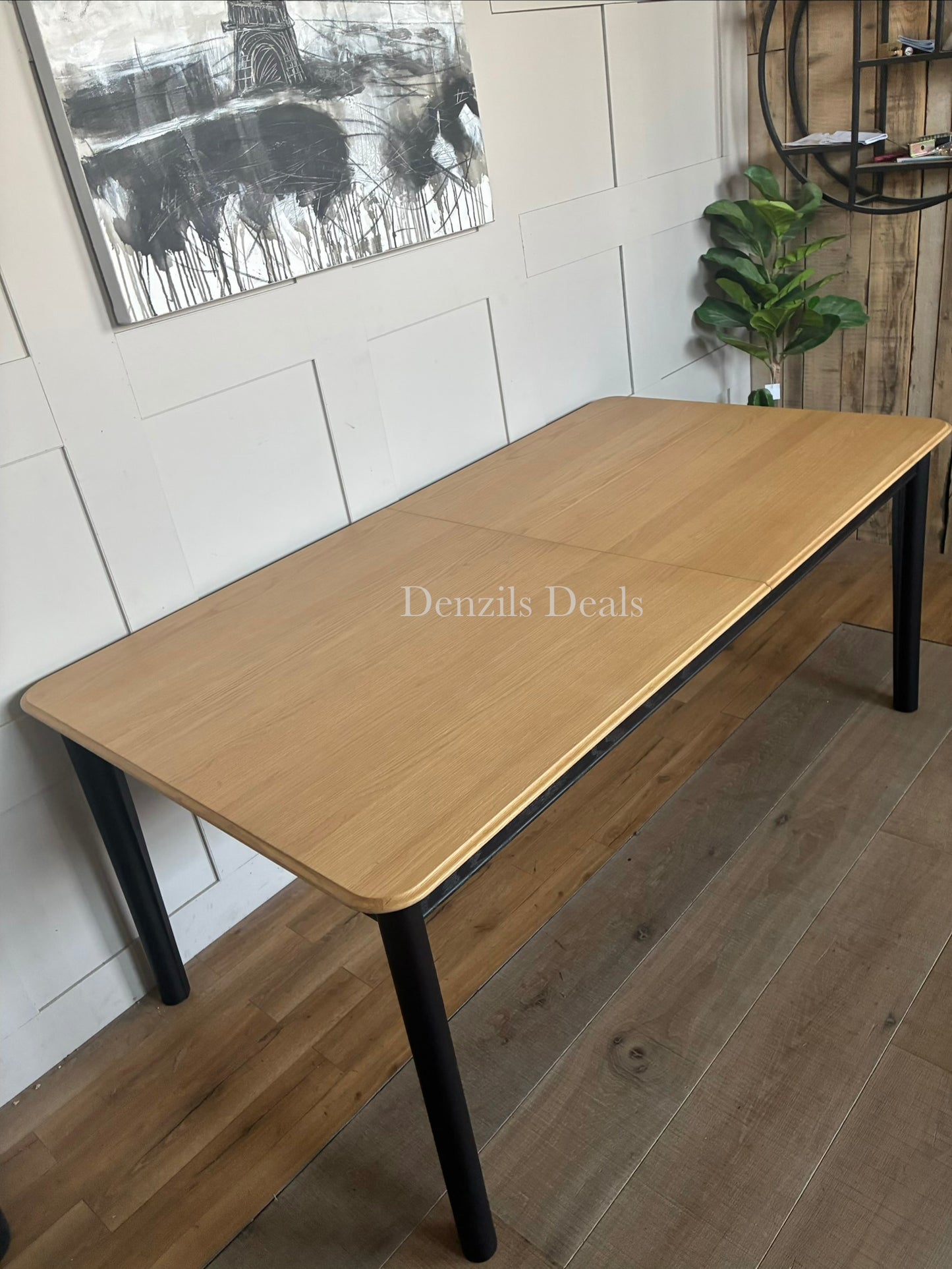 Modern rectangular dining table with a light oak wood top and contrasting matte black legs.