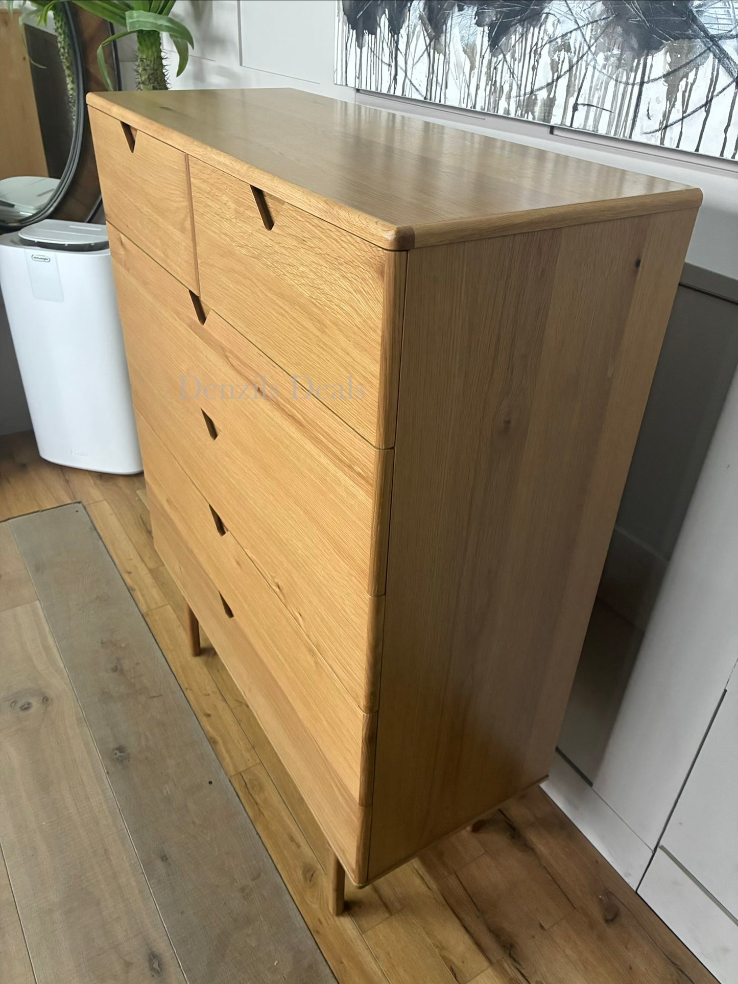 A medium-sized chest of drawers made from natural oak wood with three wide drawers and integrated handle-less design. It sits on four elegantly curved legs, showcasing a warm wood grain and a modern, minimalist silhouette.