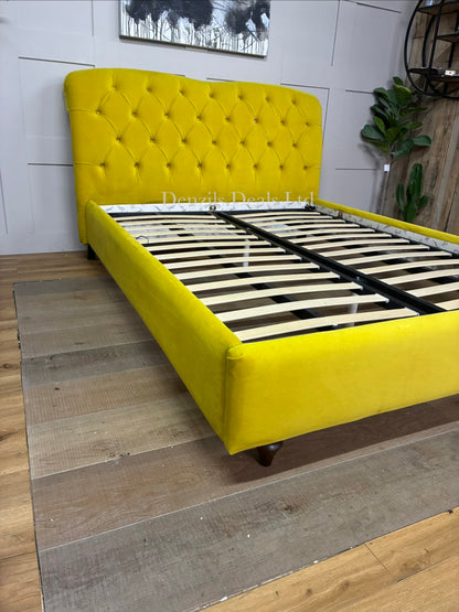Joules Windsor king-size bed frame in mustard yellow velvet from DFS, featuring a button-backed Chesterfield headboard and turned wooden legs.