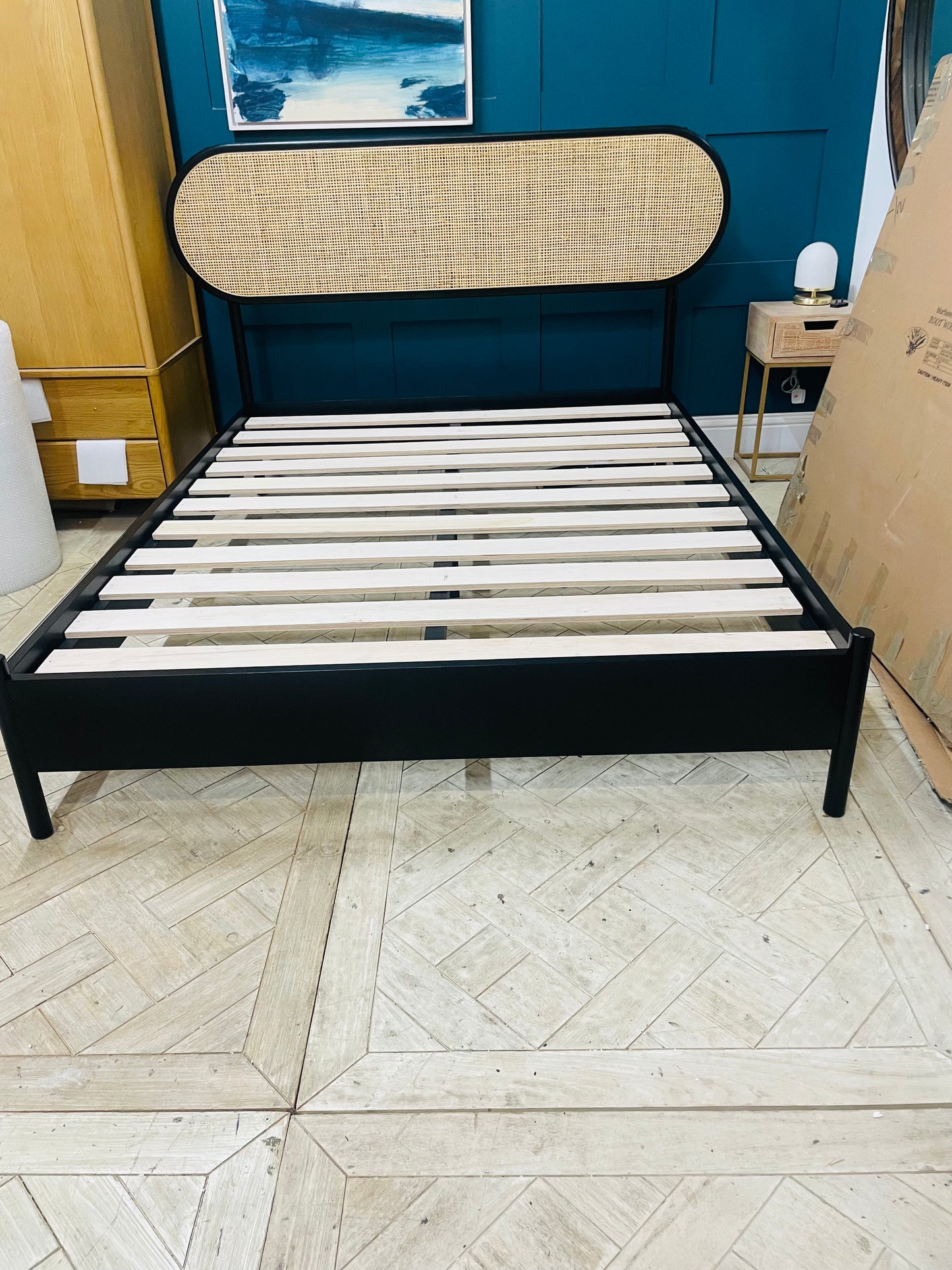 A black finish king size bed with a rattan headboard and wooden frame,