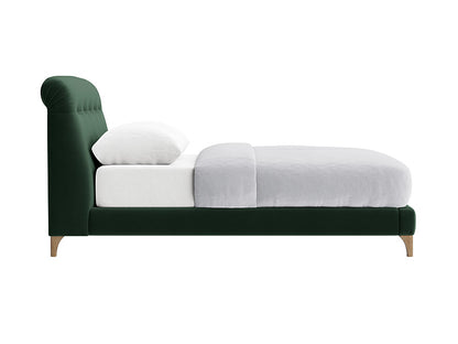 A large superking bed frame upholstered in a rich, forest-green velvet fabric. The Slumbleton design includes a thick, plush headboard that leans back slightly for comfort, supported by a sturdy wooden frame. The textured "Clever Velvet" fabric has a soft sheen and deep green hue. 