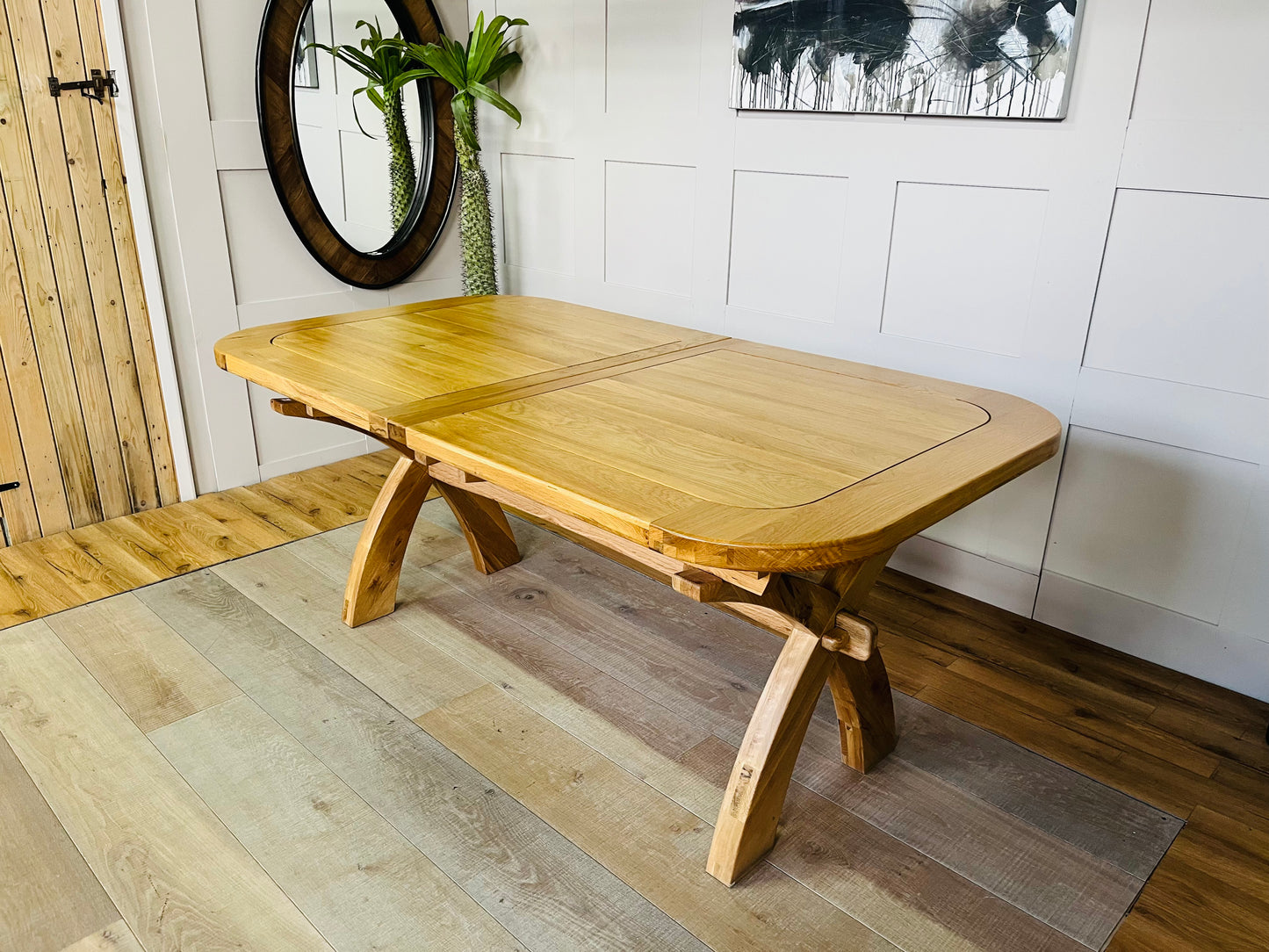 Large Hercules light oak extendable dining table by Oak Furnitureland, shown fully extended to seat 10 to 12 people, featuring a thick wooden tabletop and chunky cross legs.