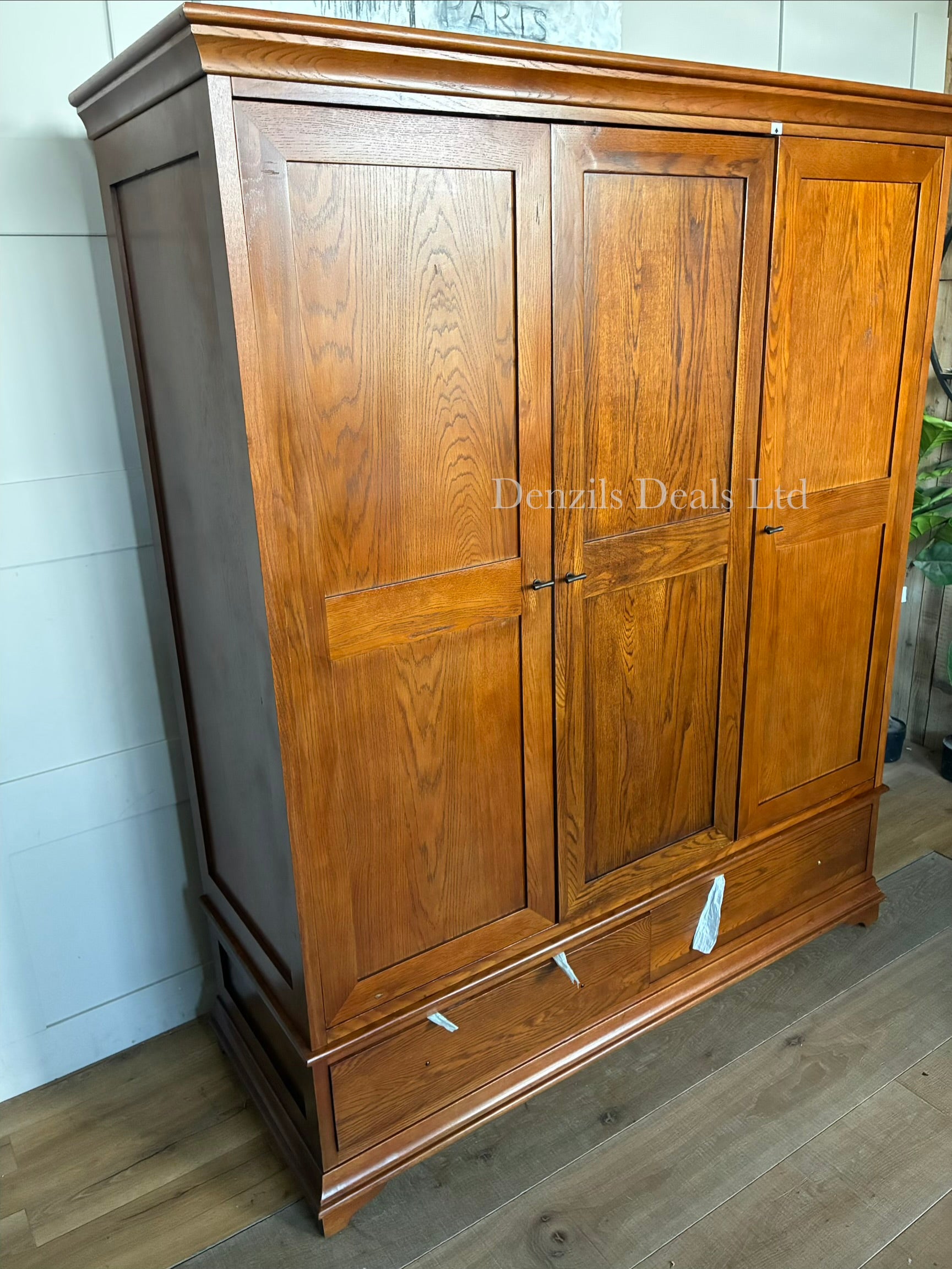 Large dark oak three-door wardrobe with a curved front profile and two drawers with antique brass-effect hardware.