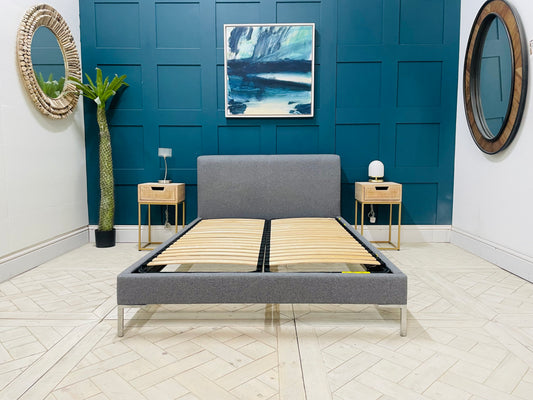 A contemporary Loaf double bed upholstered in grey fabric with a modern, low-profile frame and subtle chrome legs.