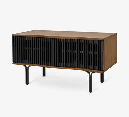 Made.com Zaragoza compact TV unit in organic walnut wood and charcoal black, featuring a contemporary slatted sliding front, subtle wavy edges, and slim metal legs