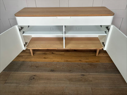 Mid-century modern inspired wide sideboard designed by Ebbe Gehl for John Lewis. The unit features two minimalist matte white cabinet doors with integrated finger-pull handles, a smooth natural oak wood top, and a matching solid oak base frame with four tapered legs