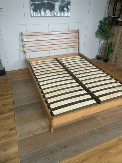 Mid-century modern king-size bed frame from the John Lewis X-Ray bedroom range, crafted from oak wood with a smooth Bianco Lacquer finish. The design features a slatted wood headboard with soft curves, sleek side panels, low-profile frame, and tapered wooden legs.