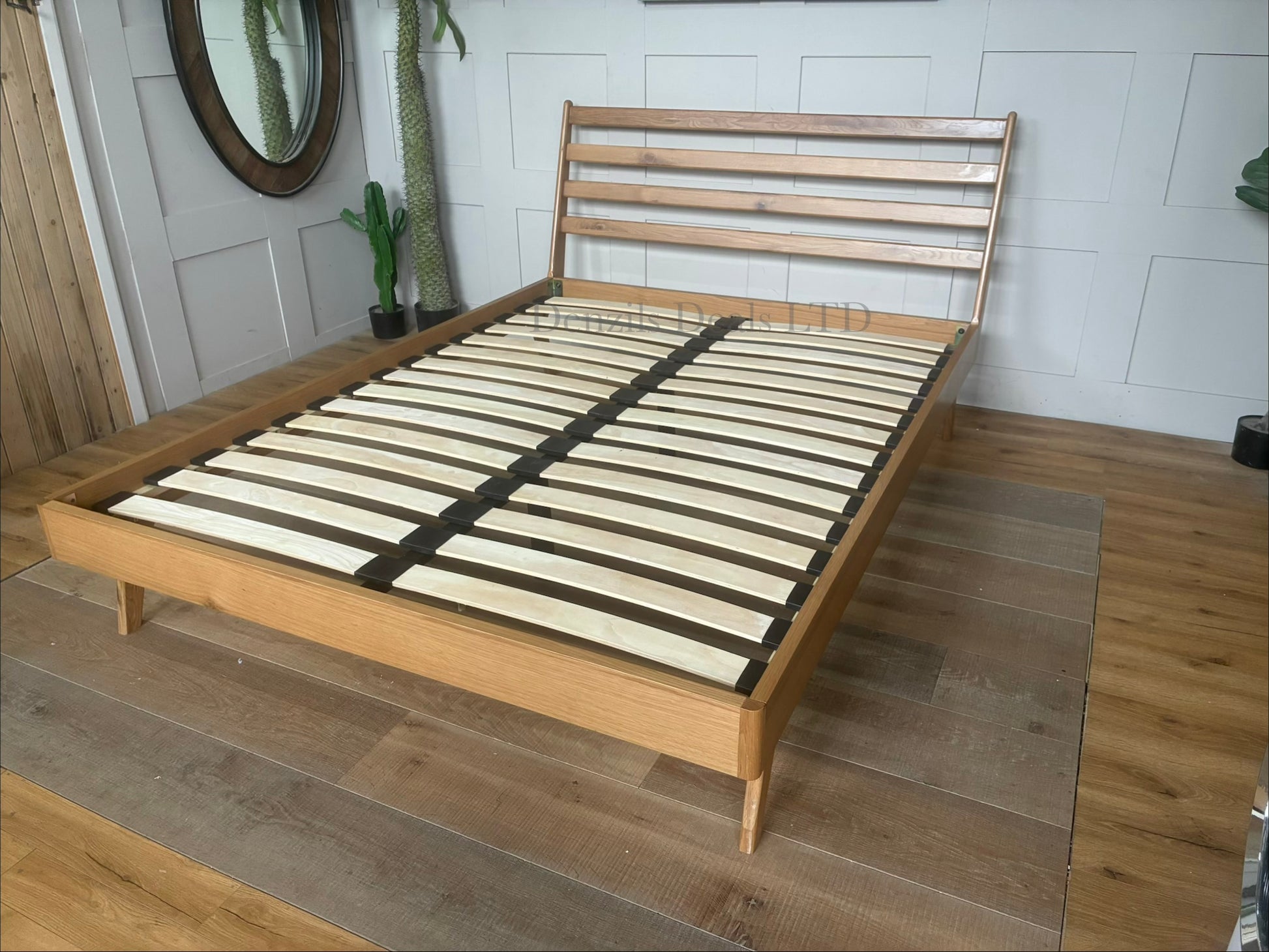 Mid-century modern king-size bed frame from the John Lewis X-Ray bedroom range, crafted from oak wood with a smooth Bianco Lacquer finish. The design features a slatted wood headboard with soft curves, sleek side panels, low-profile frame, and tapered wooden legs.