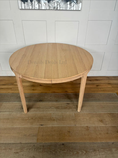 Modern dining room featuring the John Lewis Mira II round oak dining table surrounded by matching chairs on a neutral rug.