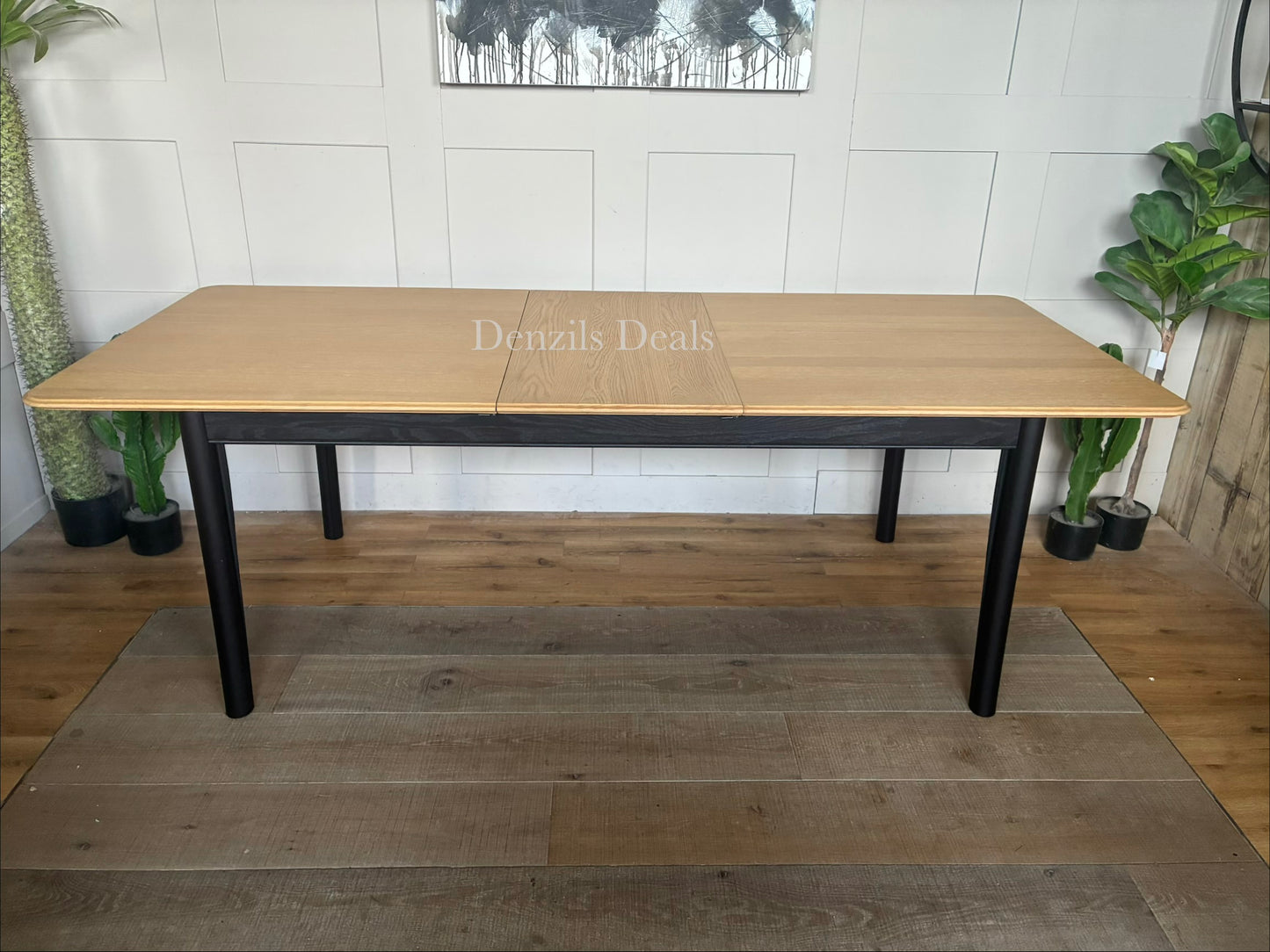 Modern John Lewis Stanton extending dining table featuring a natural light oak rectangular tabletop supported by angular, black metal or painted wooden legs.