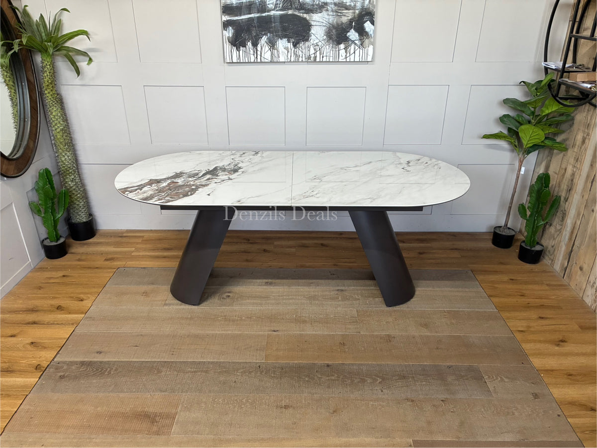 Modern Lorea extending dining table by Dwell, featuring a luxurious pill-shaped white marble-effect ceramic tabletop resting on contemporary grey iron sloping legs.