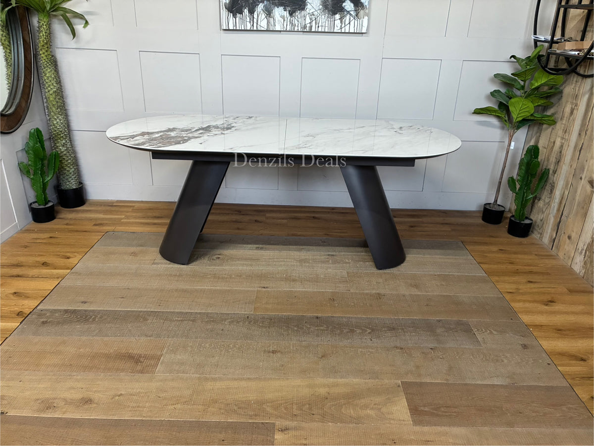 Modern Lorea extending dining table by Dwell, featuring a luxurious pill-shaped white marble-effect ceramic tabletop resting on contemporary grey iron sloping legs.