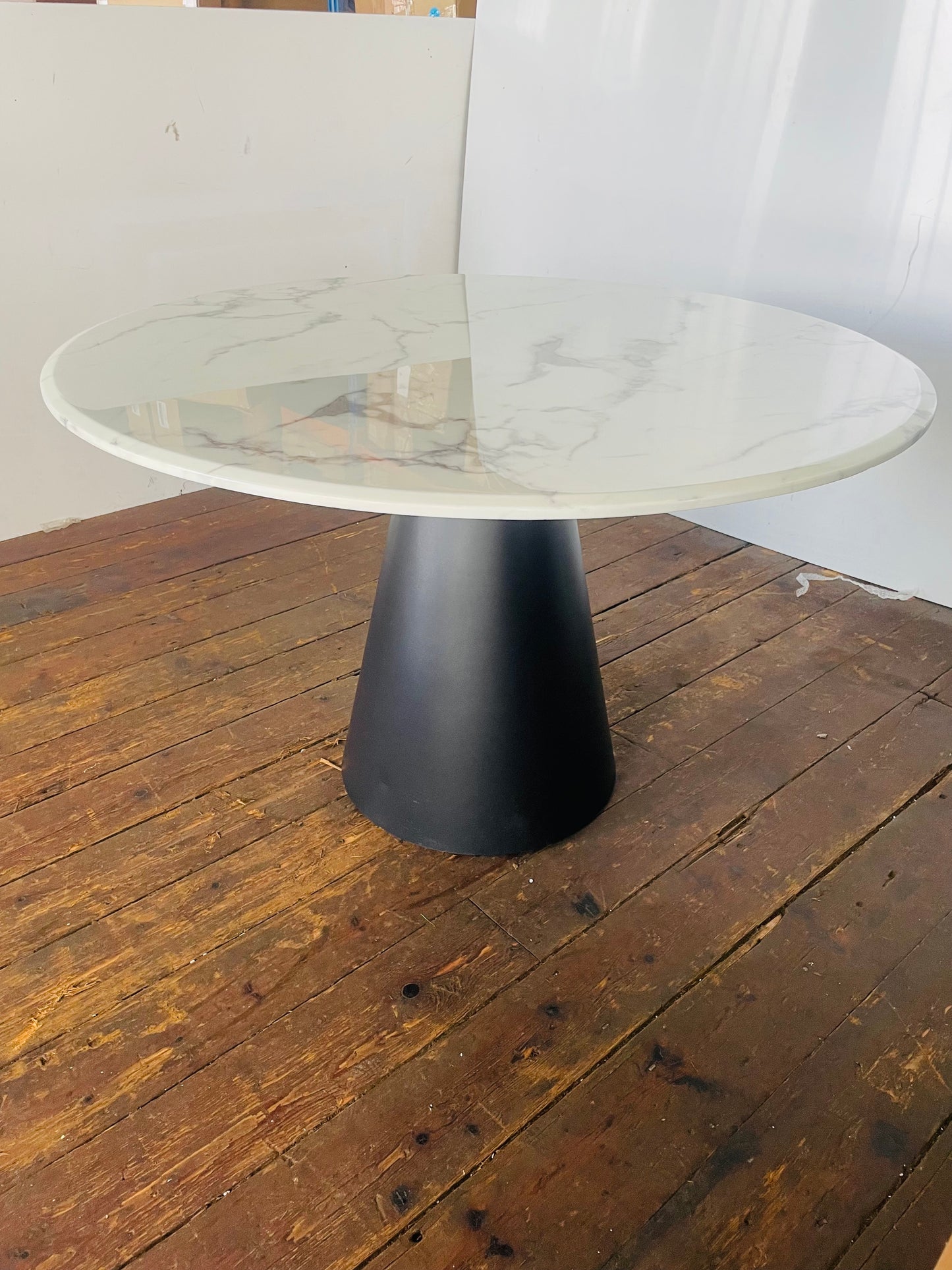 Modern Richmond Degas 120cm circular dining table. The table features a smooth, polished white faux-marble top with subtle grey veining, supported by a minimalist black stainless steel leg frame. 