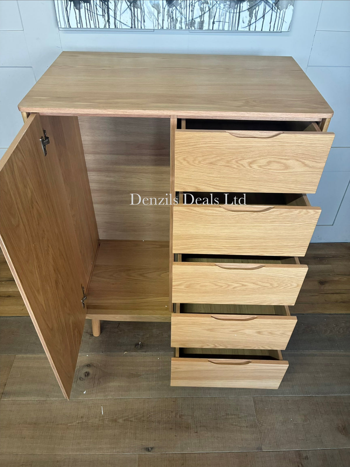 Modern and compact low freestanding wardrobe crafted from natural grain solid oak and wood veneers. The left side features a hinged door opening to a compact hanging rail area, while the right side is configured with five stacked storage drawers. The unit stands on short, subtly splayed wooden legs and highlights a smooth, lacquered natural finish