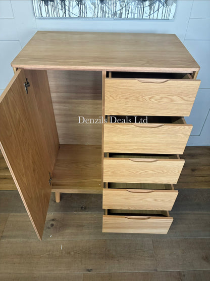 Modern and compact low freestanding wardrobe crafted from natural grain solid oak and wood veneers. The left side features a hinged door opening to a compact hanging rail area, while the right side is configured with five stacked storage drawers. The unit stands on short, subtly splayed wooden legs and highlights a smooth, lacquered natural finish