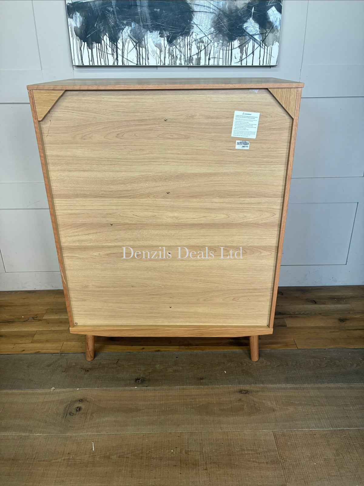 Modern and compact low freestanding wardrobe crafted from natural grain solid oak and wood veneers. The left side features a hinged door opening to a compact hanging rail area, while the right side is configured with five stacked storage drawers. The unit stands on short, subtly splayed wooden legs and highlights a smooth, lacquered natural finish
