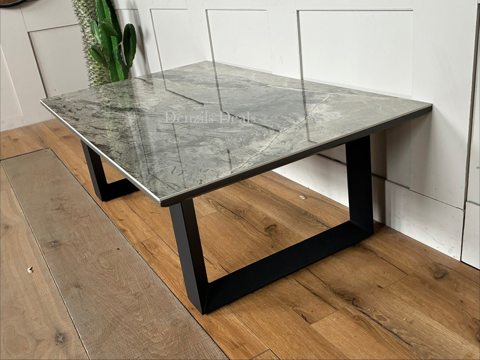 Modern coffee table featuring a coated grey stone and ceramic top with geometric steel legs.