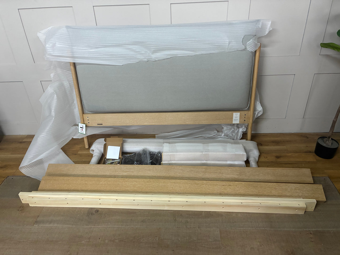 Modern double bed frame featuring a light natural oak wooden base and a soft, low-profile upholstered pillow headboard in grey fabric