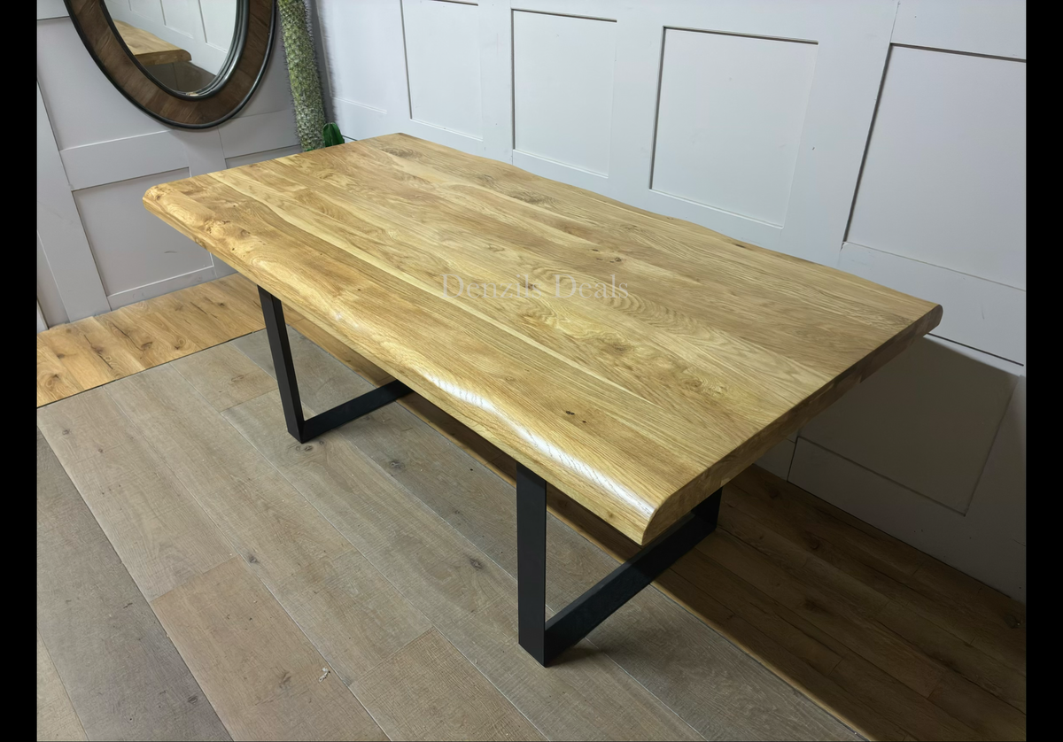 Modern industrial dining room setting featuring the Oak Furnitureland Brooklyn 8-seater dining table. The table showcases a solid natural oak tabletop with distinctive wood grain patterns and curved, wavy live edges, supported by dark, industrial-style metal legs