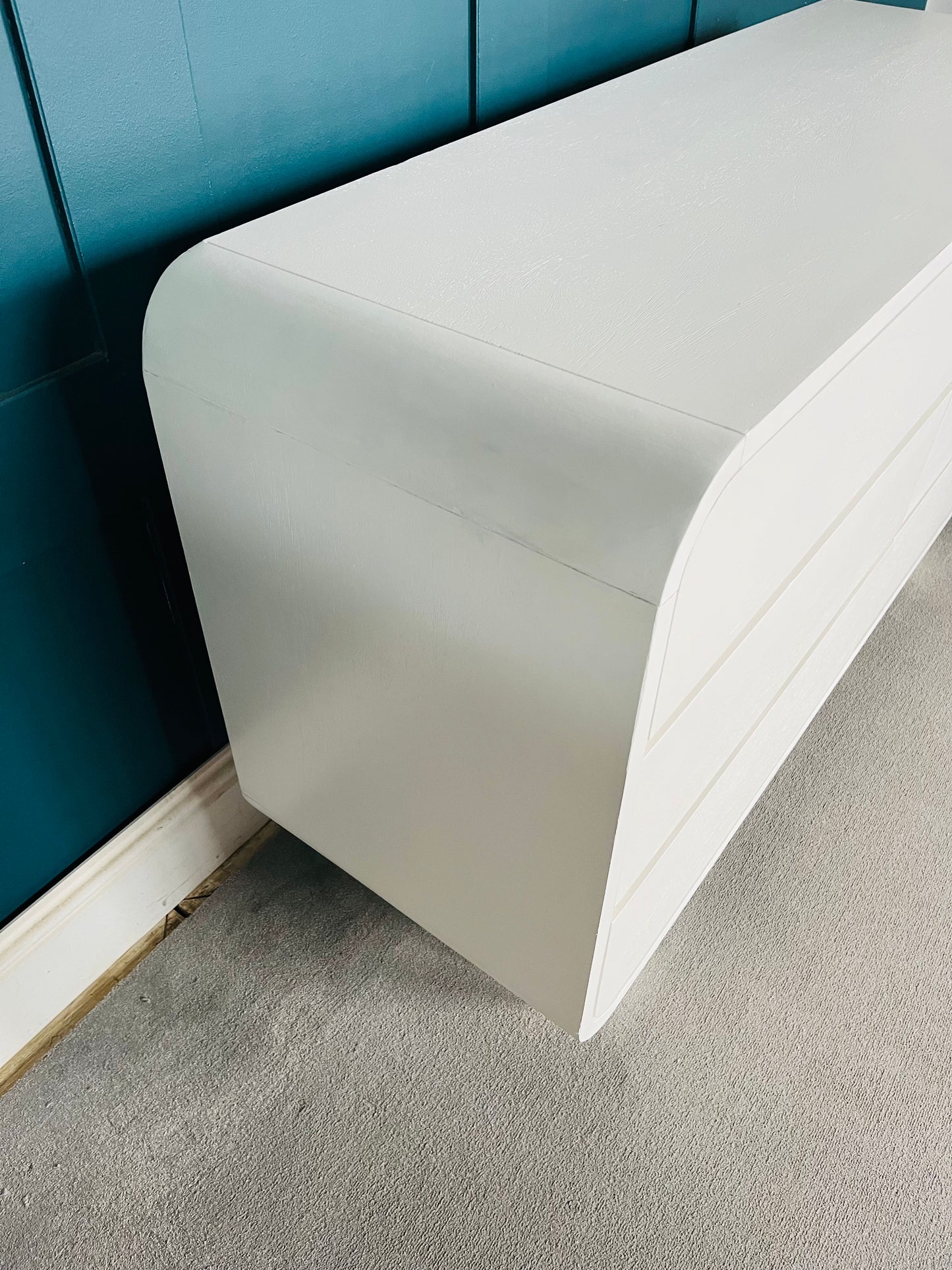 Modern low-slung bedroom dresser crafted from white-stained mango wood, featuring six spacious drawers with integrated grooved handles, soft curved corners, and two thick cylindrical block feet