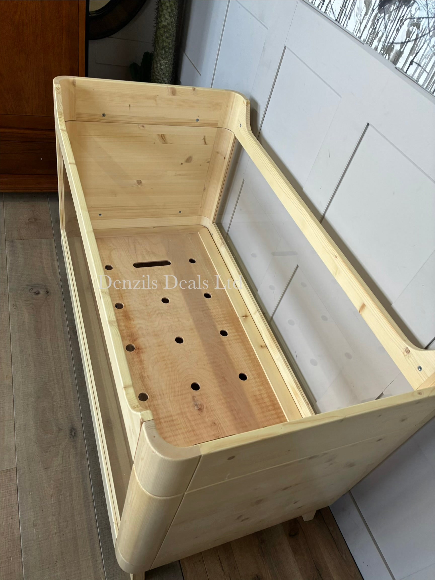 Natural wood baby cot bed with transparent acrylic sides.
