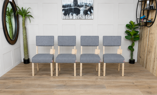 A set of four Nkuku Nadeeka dining chairs featuring soft grey linen upholstery with a subtle stripe pattern and a light-toned mango wood frame