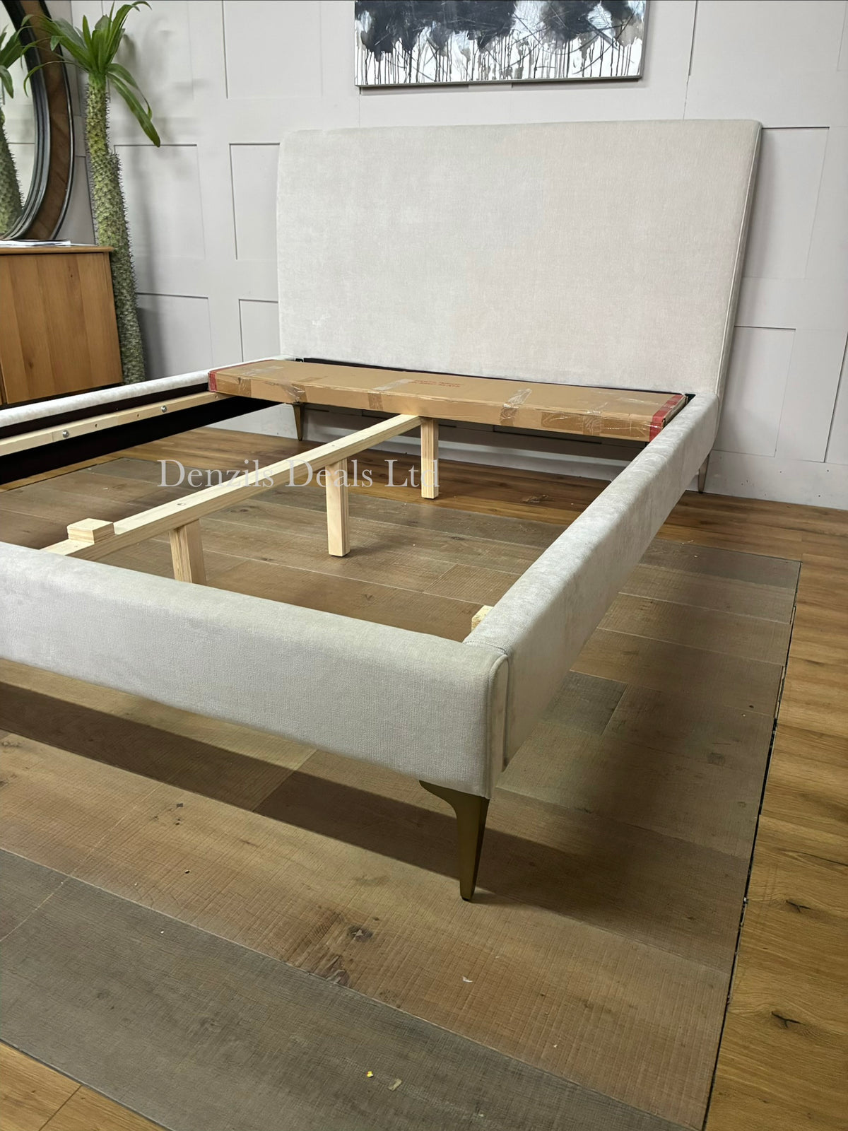 Nontufted West Elm Andes king-size bed upholstered in sand-colored fabric, supported by champagne bronze metal legs.