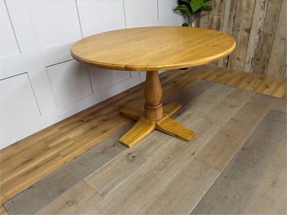 Oak Furnitureland Henley range round dining table in natural oak. The image features a solid hardwood circular top with visible wood grains, supported by an ornate, chunky carved central pedestal column base resting on a stable cross-shaped foot