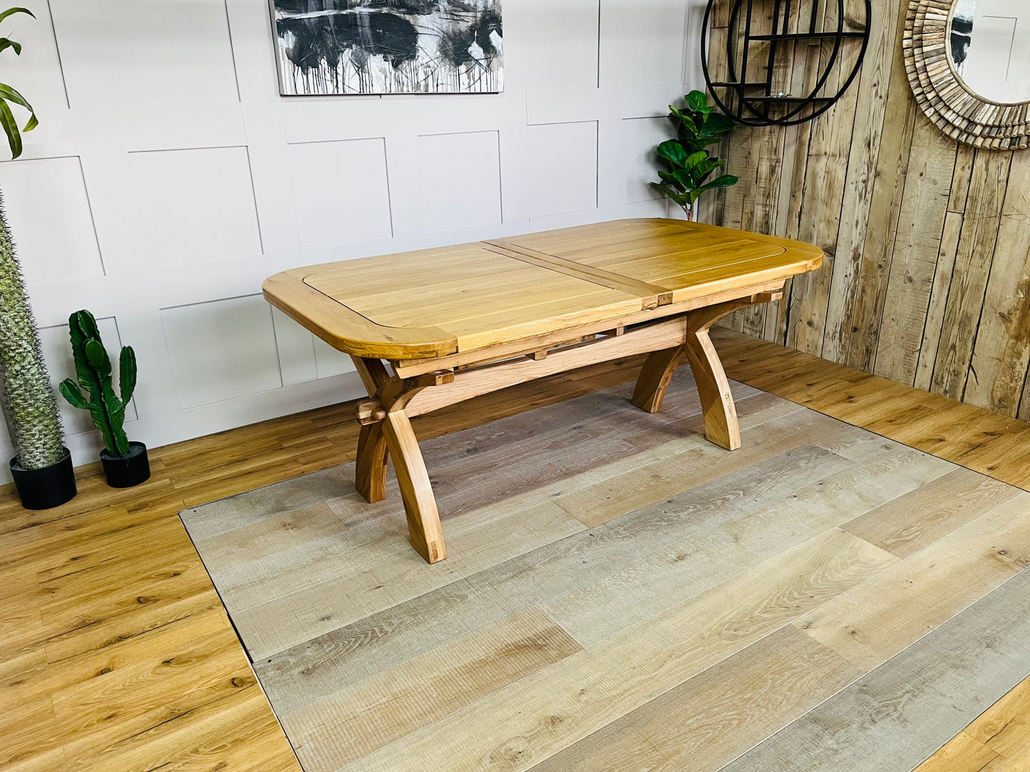 Oak Furnitureland Hercules natural solid oak extending dining table with cross-arched legs, shown at its full 280cm length to seat 10 to 12 people."