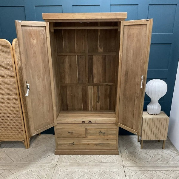 Freestanding Puji wardrobe crafted from solid natural teak wood. The piece features two large, hinged cabinet doors that open to full hanging space, set above three wide, horizontally aligned drawers at the base, and displays a prominent, rich grain finish."