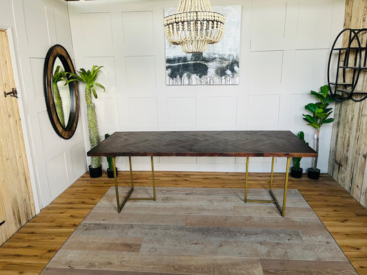 Rectangular Dutchbone Class dining table featuring a rich dark brown acacia wood top with an intricate herringbone pattern and a contrasting geometric brass-coated metal base.