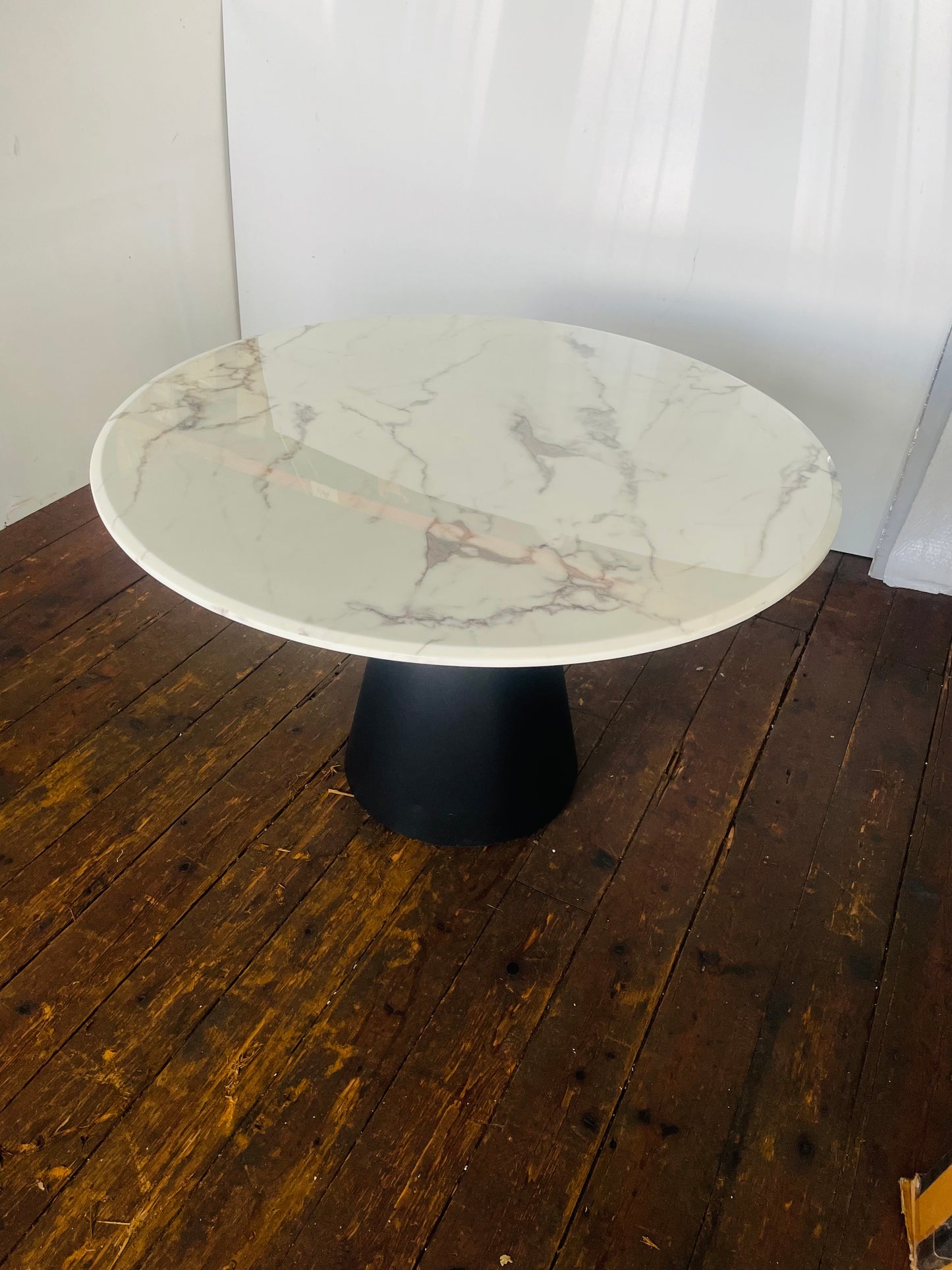 Richmond Degas 120cm round dining table featuring a sleek, smooth white faux marble top resting on a bold, conical matte black metal pedestal base