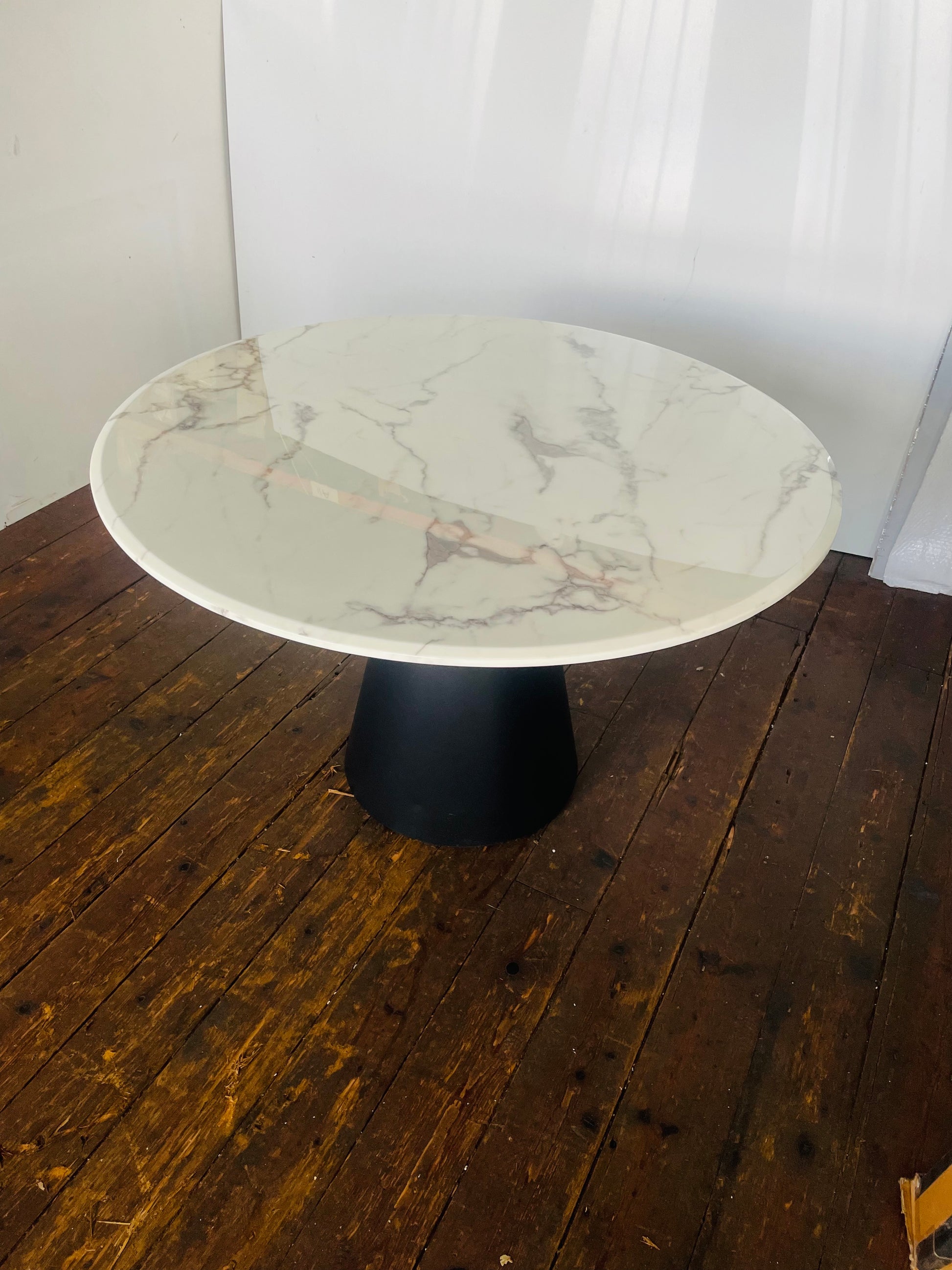 Richmond Degas 120cm round dining table featuring a sleek, smooth white faux marble top resting on a bold, conical matte black metal pedestal base